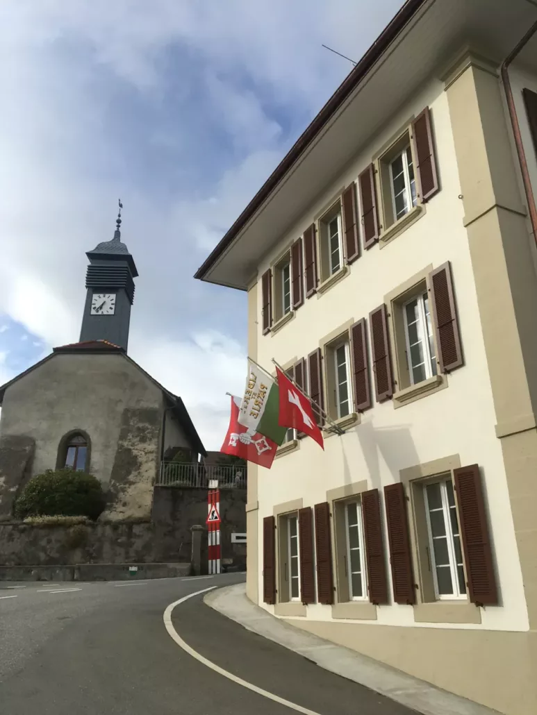 Église et bâtiment communal de Chavannes-sur-Moudon pavoisé aux drapeaux suisse, vaudois et communal